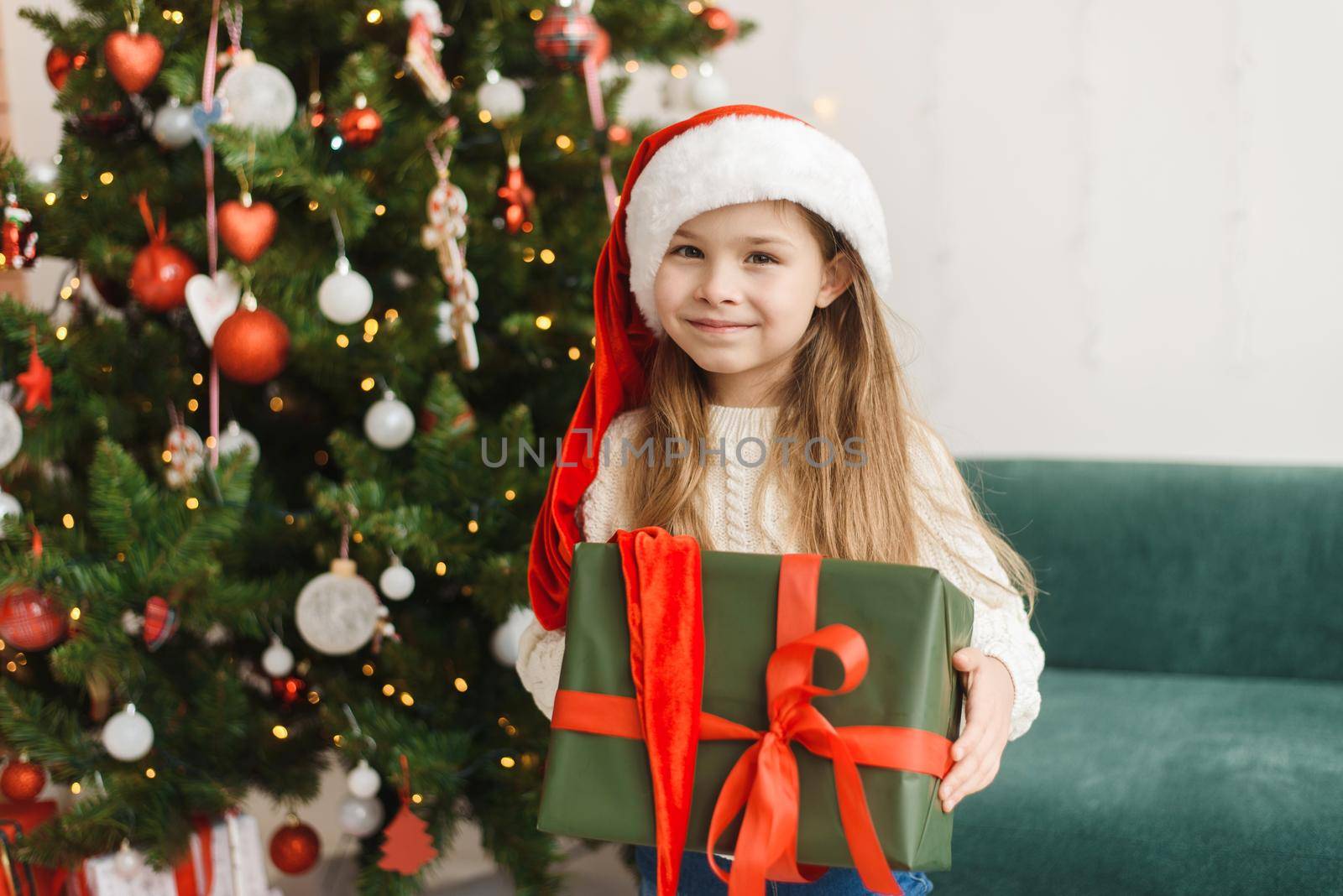 Festive cute little girl opens a gift at home in the living room. Christmas and New Year