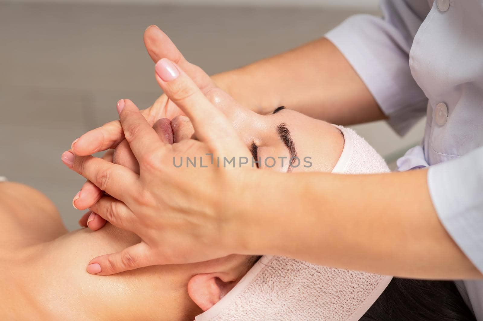 Beautiful caucasian young woman getting a facial massage at a beauty salon