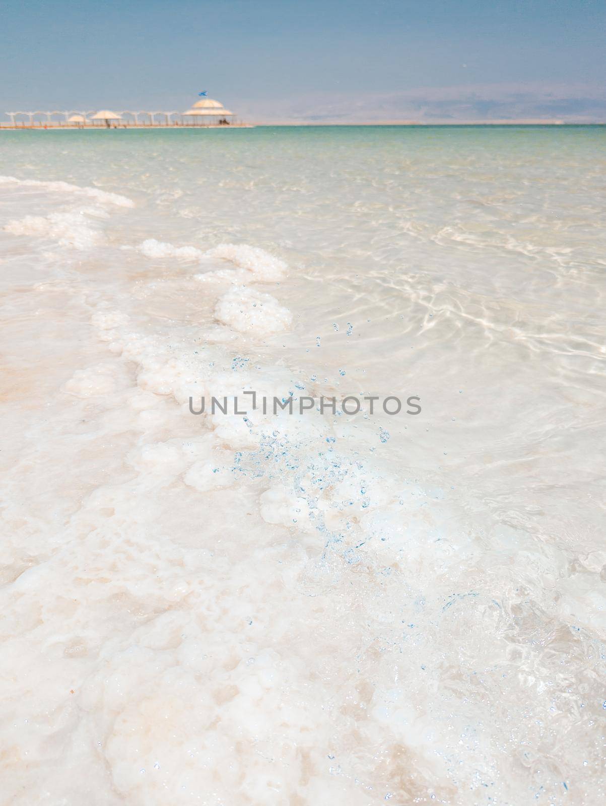 Landscape view on Dead Sea salt crystals formations, clear cyan green calm water at Ein Bokek beach, Israel