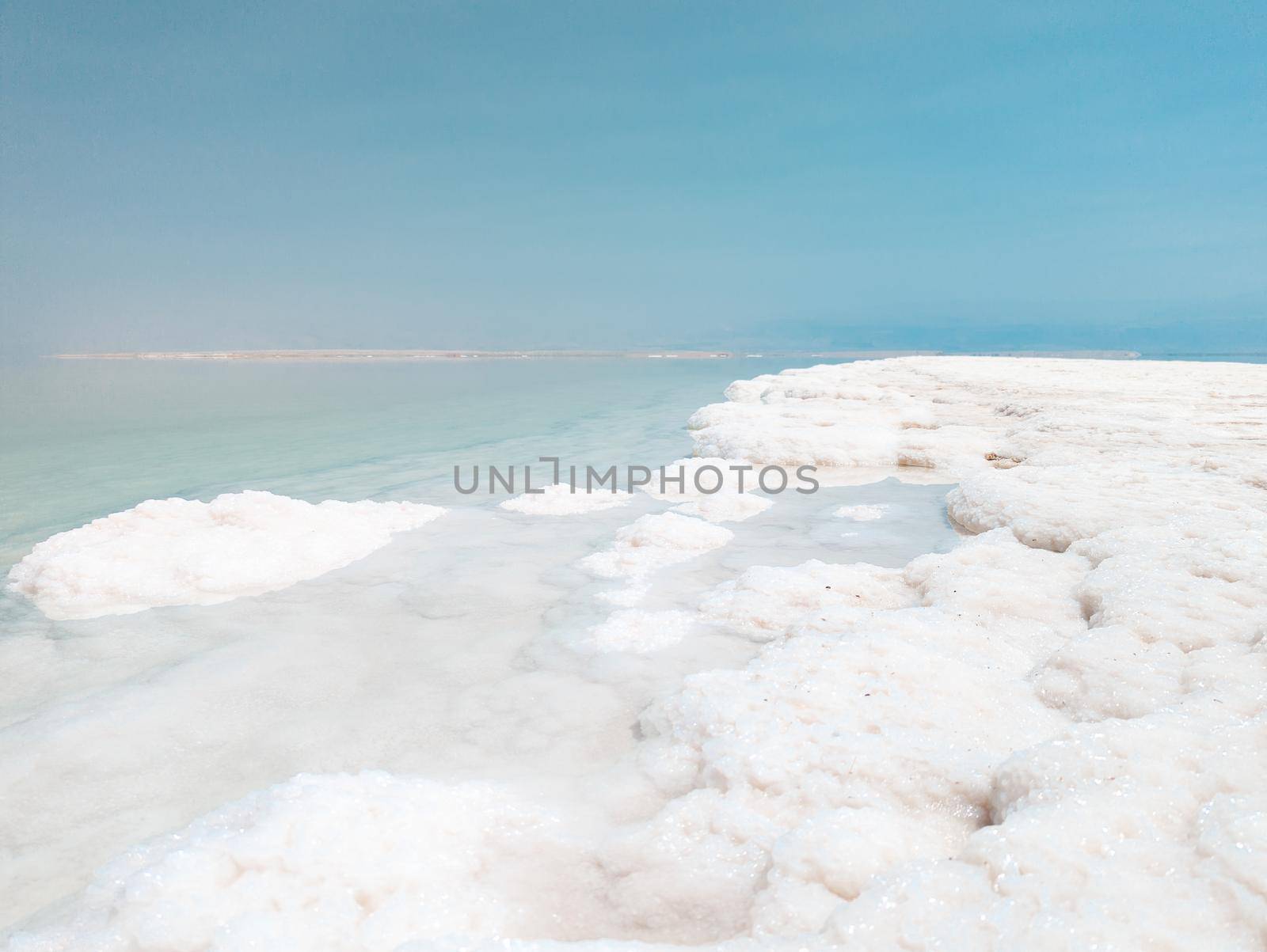 Landscape view on Dead Sea salt crystals formations, clear cyan green calm water at Ein Bokek beach, Israel