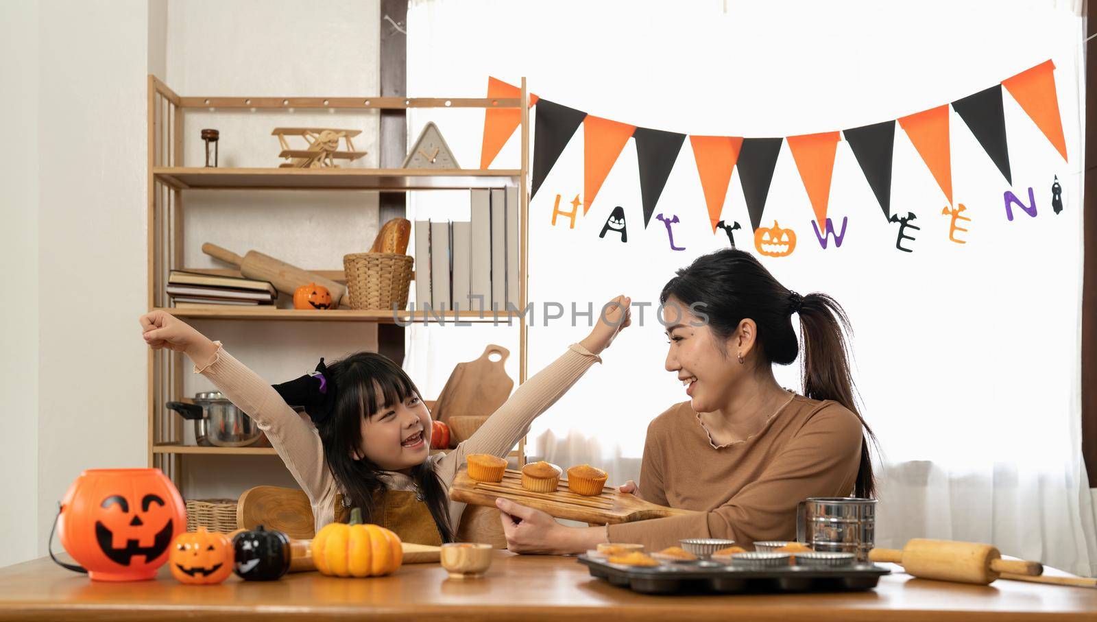 Happy smiling mom in the kitchen bakes cookies with her daughter