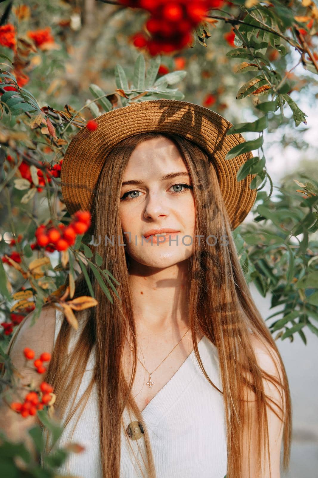 A beautiful blonde girl in a hat with long hair, on a walk in the autumn season. Portrait of a woman at a rowan tree by Annu1tochka