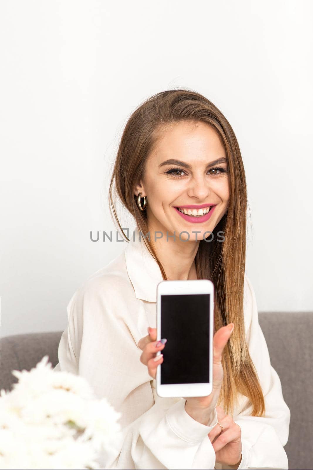 Two smiling female doctors wearing white medical gowns with empty smartphone screen in a medical office, mockup, copy space