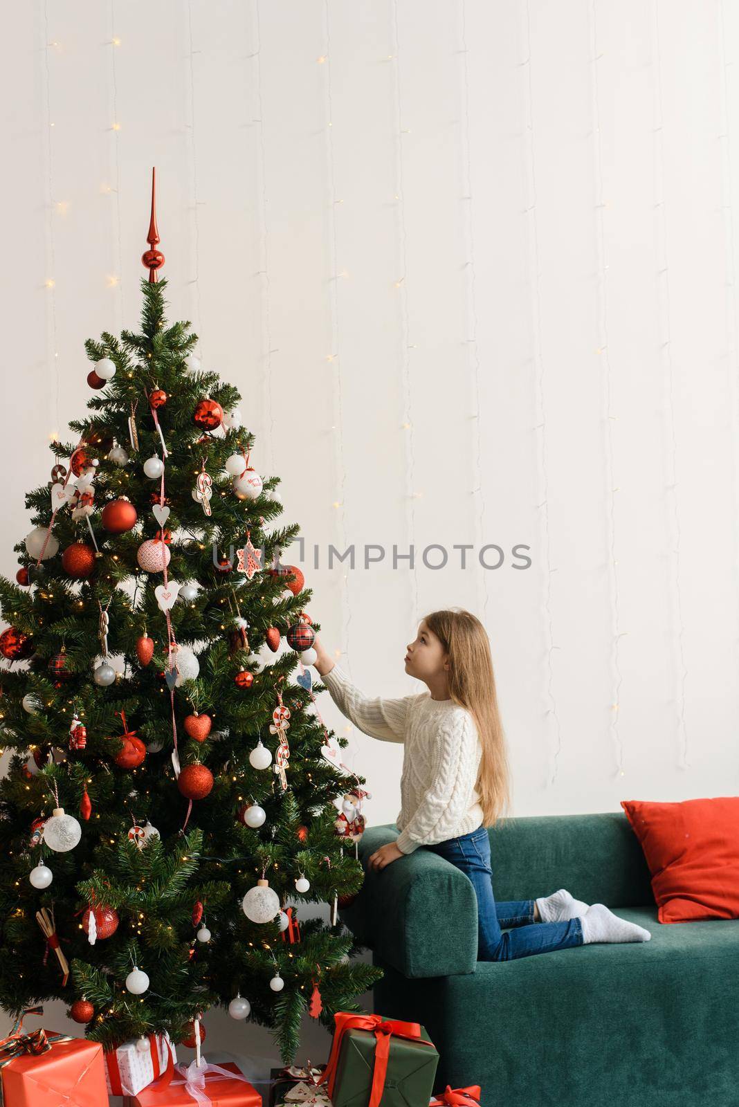 Portrait of a smiling little girl decorating the Christmas tree. by etonastenka