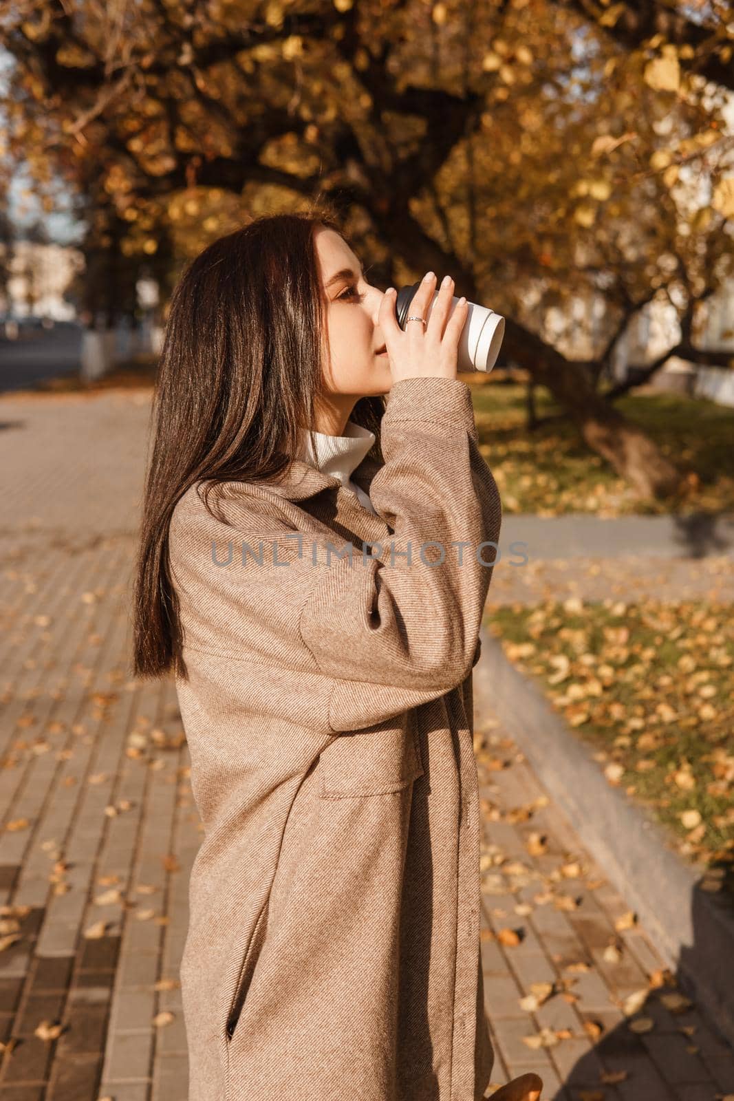 A stylish brunette woman walks around the autumn city. The season is autumn.
