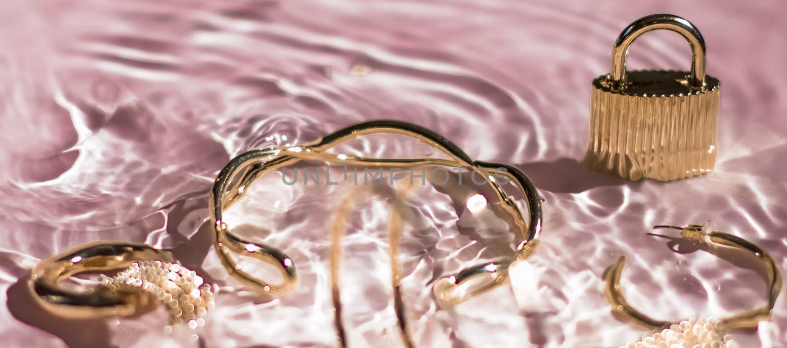 Golden bracelets, earrings, rings, jewelery on pink water background, luxury glamour and holiday beauty design for jewelry brand ads by Anneleven