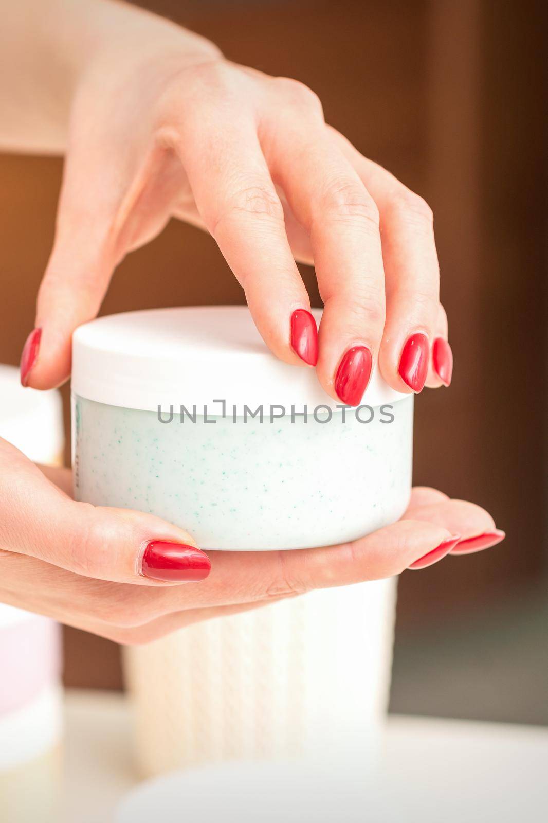 The woman opens the lid holding a jar of moisturizing cream, mockup, copy space, closeup. by okskukuruza