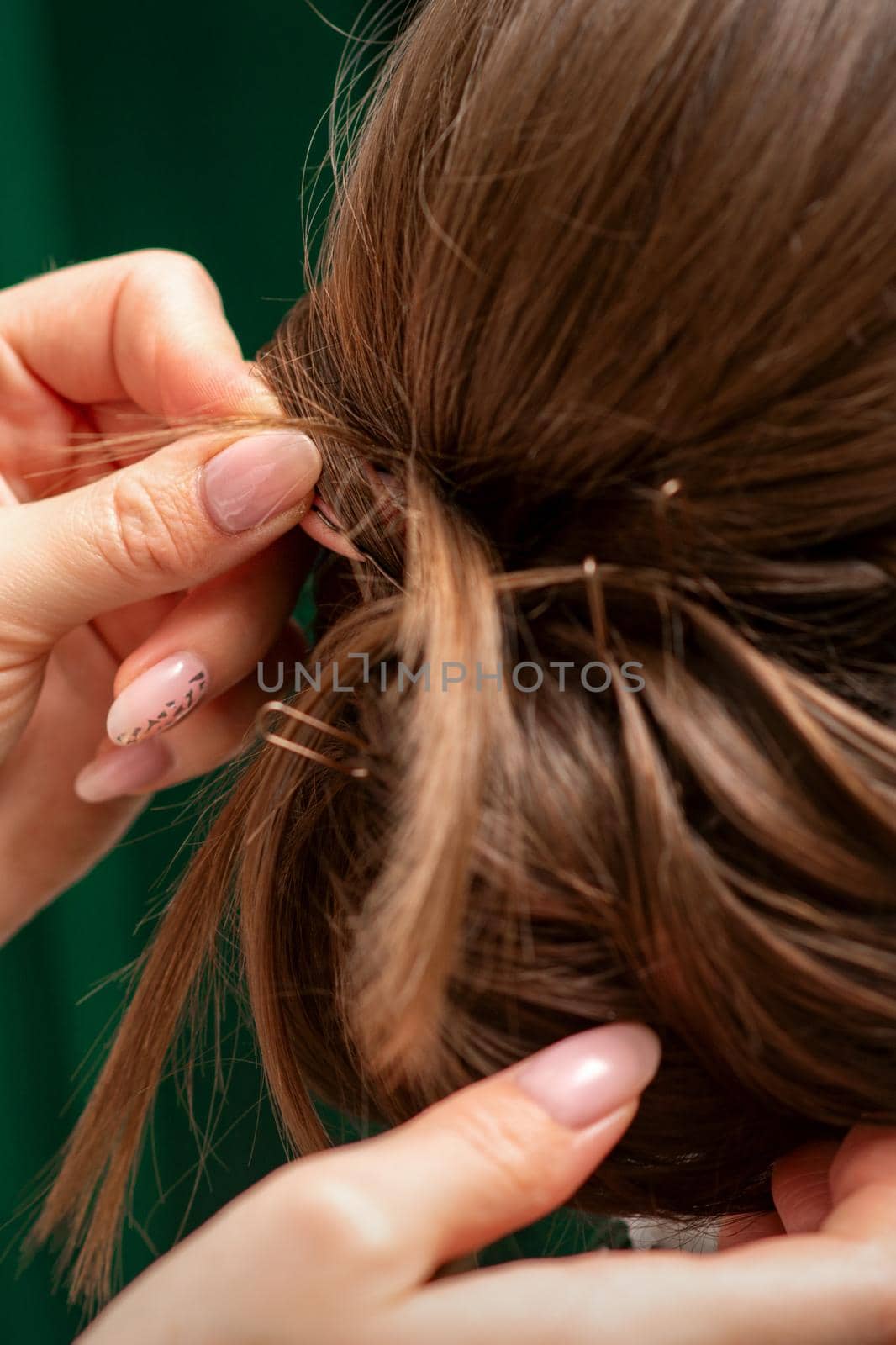 Hairdresser makes hairstyles for a young woman in beauty salon close up. by okskukuruza