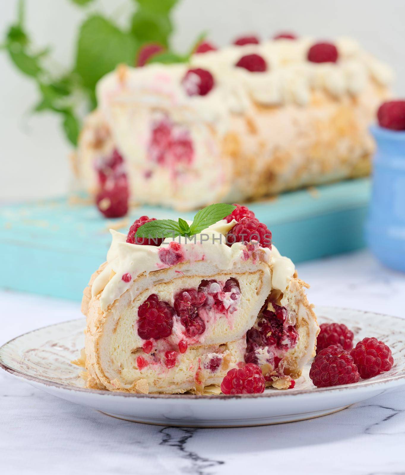 Baked meringue roll with cream and fresh red raspberry, white background	