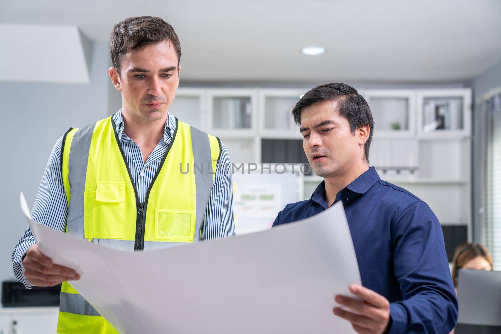 Competent investor investor discuss and brainstorm with engineer on blueprints, construction plans before putting them into action. Professional establishing investment plan for engineering projects.