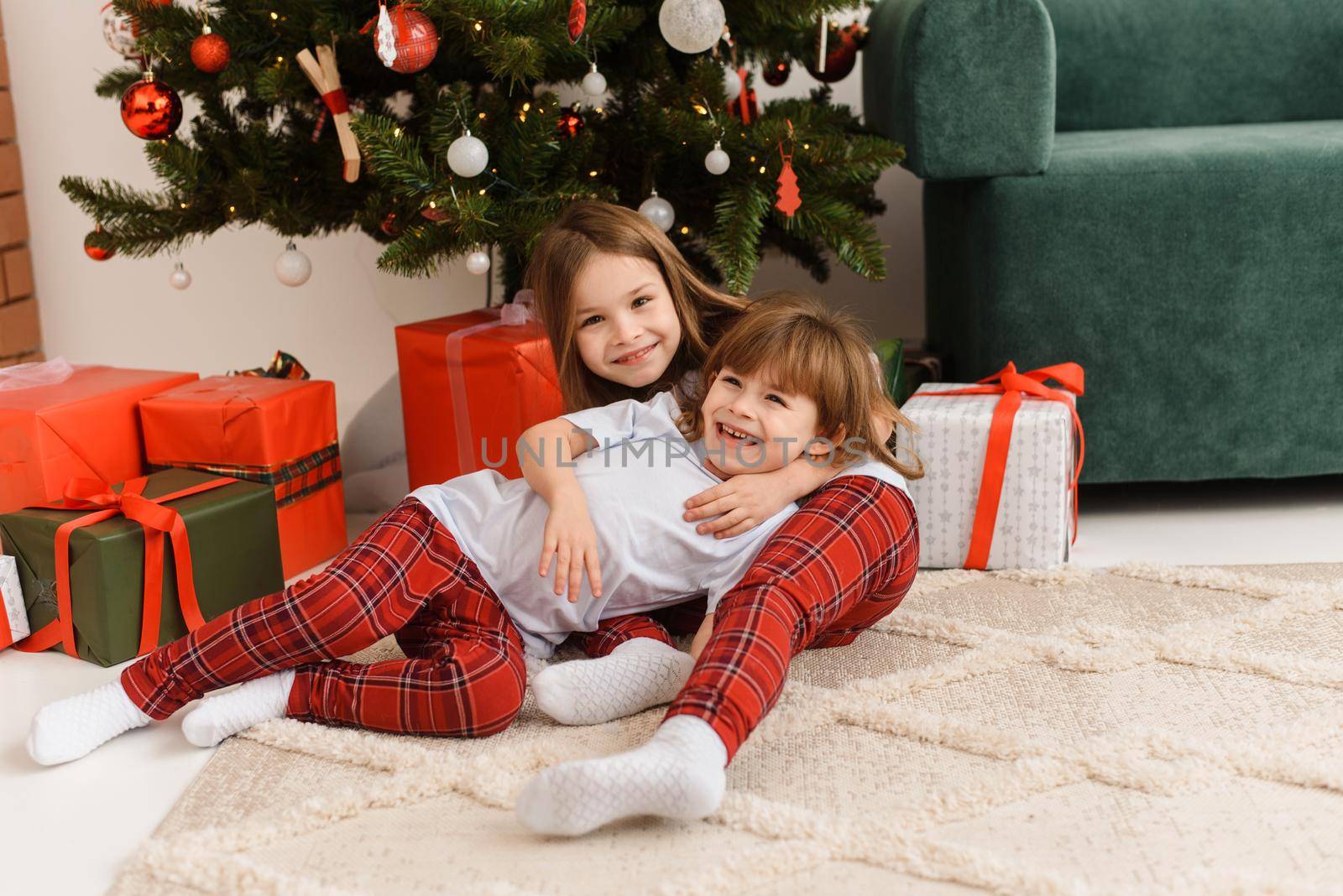 Portrait of two little sisters having fun and fooling around on Christmas morning near the Christmas tree