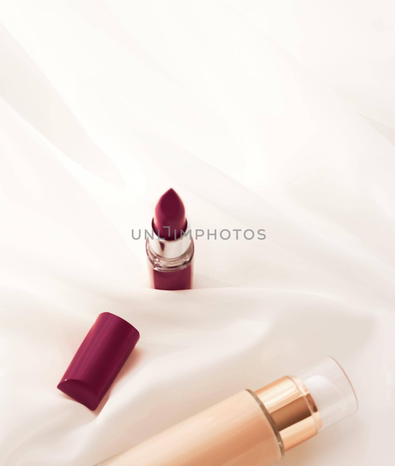 Beige tonal cream bottle make-up fluid foundation base and dark lipstick on silk background, cosmetics products as luxury beauty brand holiday design by Anneleven