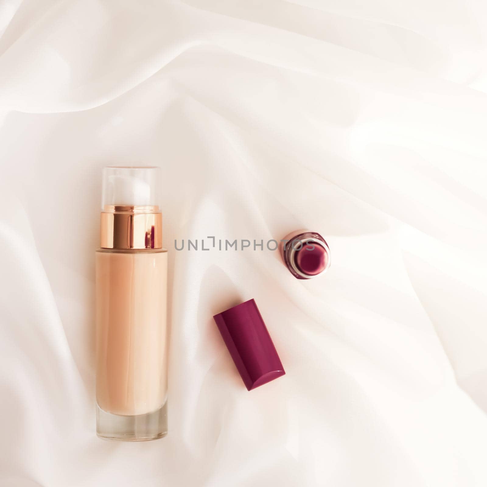 Beige tonal cream bottle make-up fluid foundation base and dark lipstick on silk background, cosmetics products as luxury beauty brand holiday design by Anneleven
