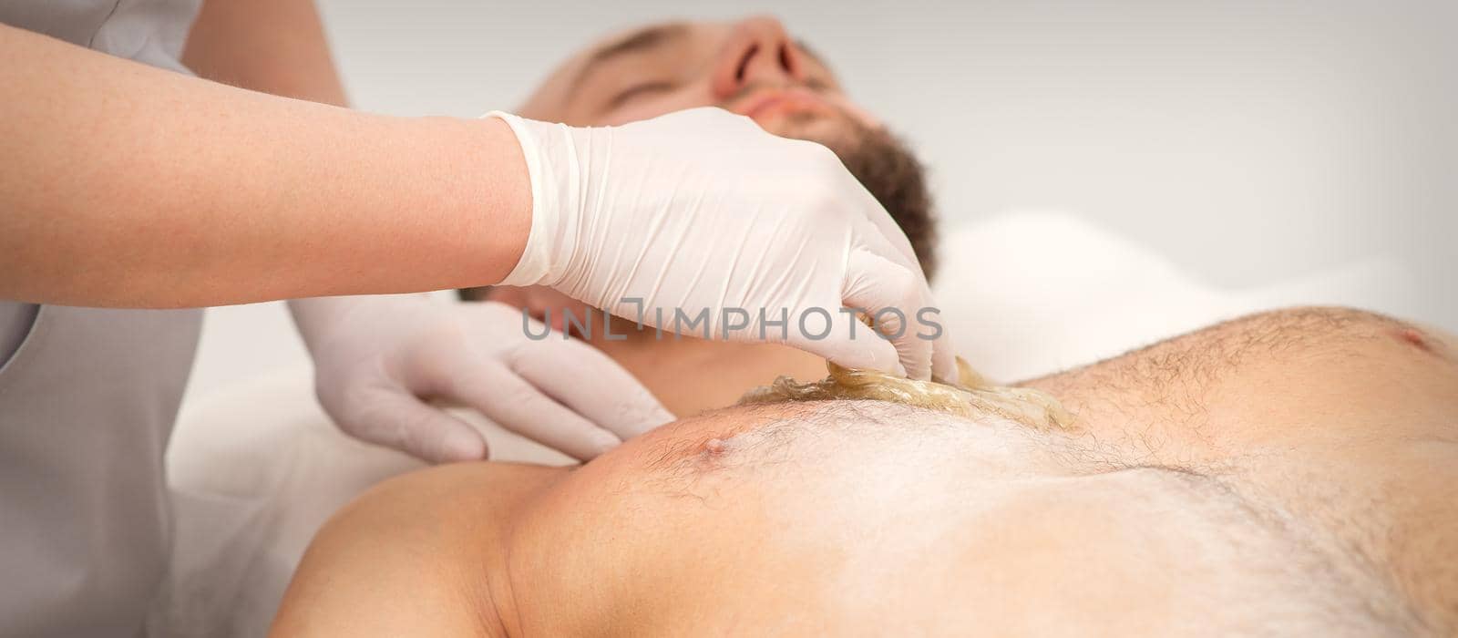 Epilation chest of a young male with the liquid wax paste in a beauty salon