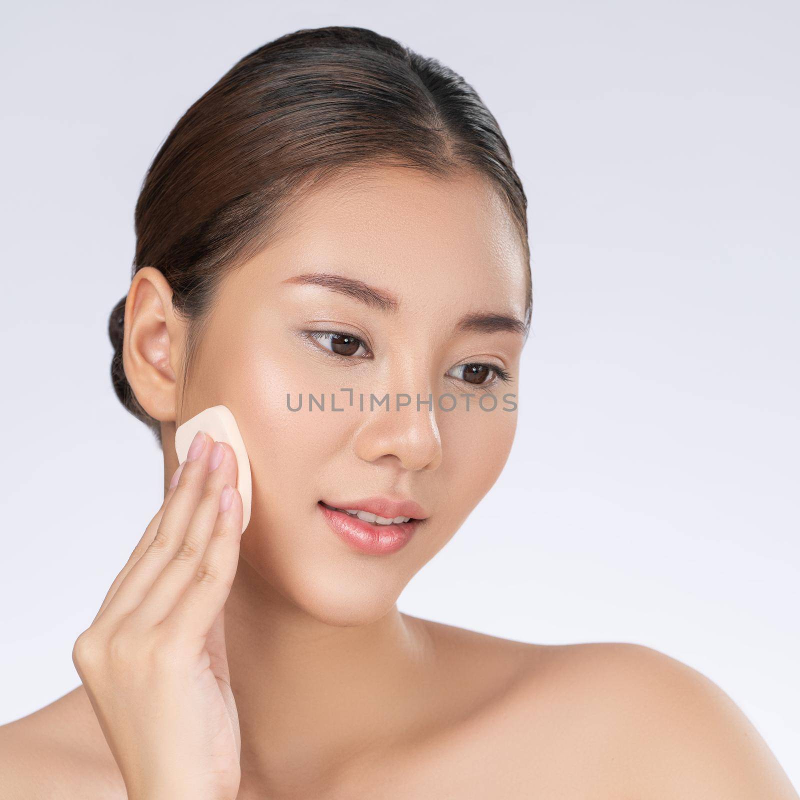 Gorgeous woman applying her cheek with dry powder. Portrait of younger with perfect makeup and healthy skin concept.