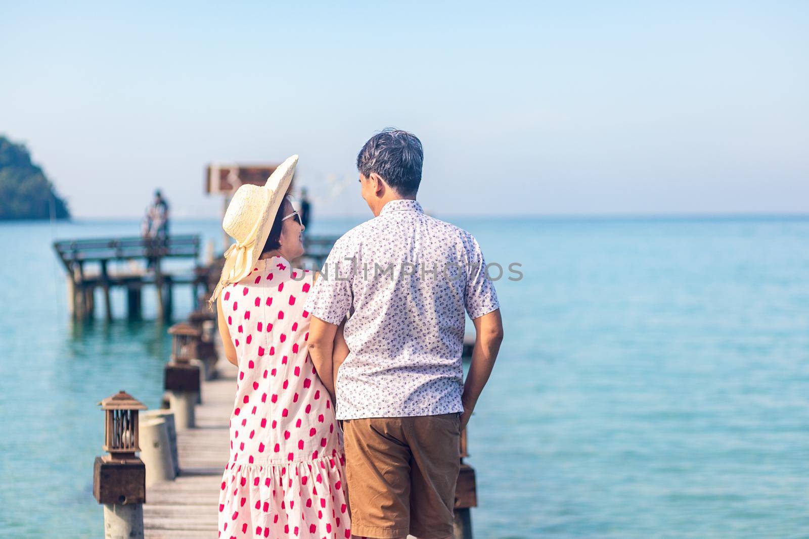 Middle aged couple relaxing on wooden pier in holiday at koh kood ,Thailand.