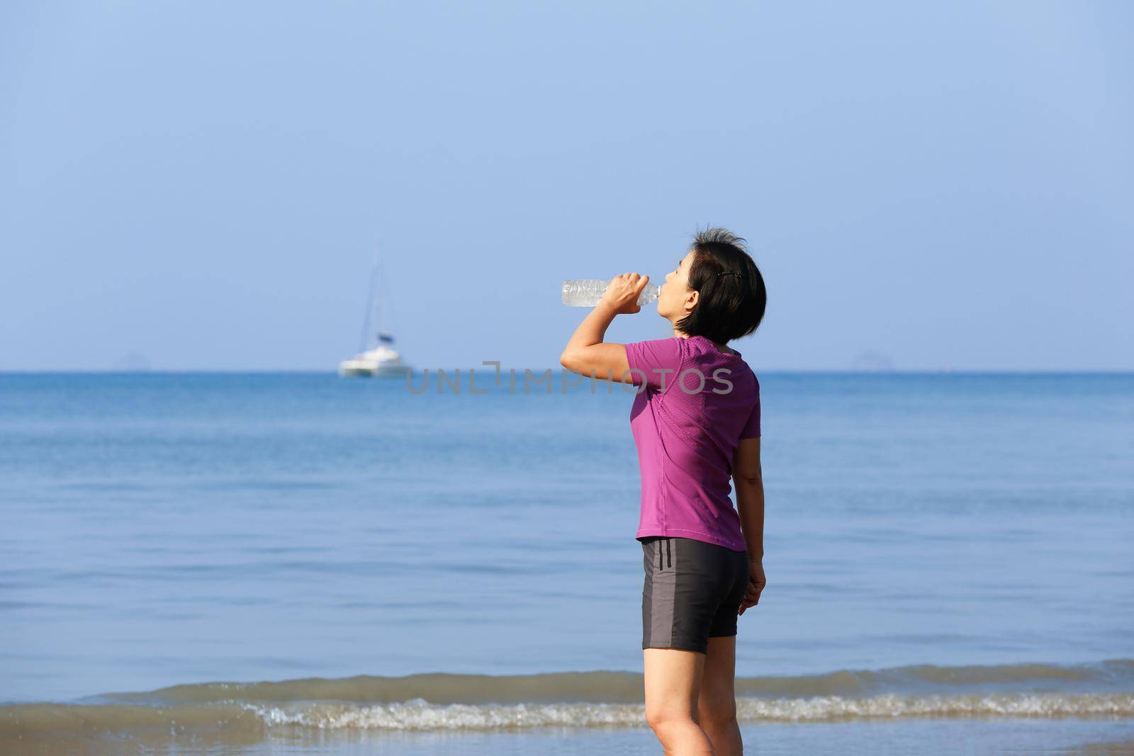 Fitness runner woman on ao nang beach , drinking water,Krabi , Thailand by toa55