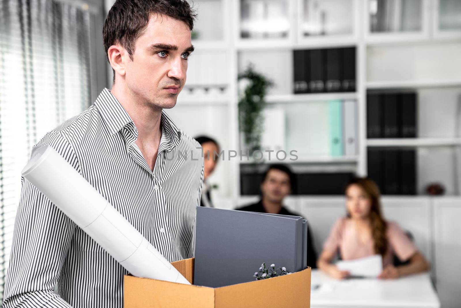 Depressed and disappointed employee packing his belongings after being fired for not being competent. Gossiped by his colleagues behind his back. Layoff due to economic depression.