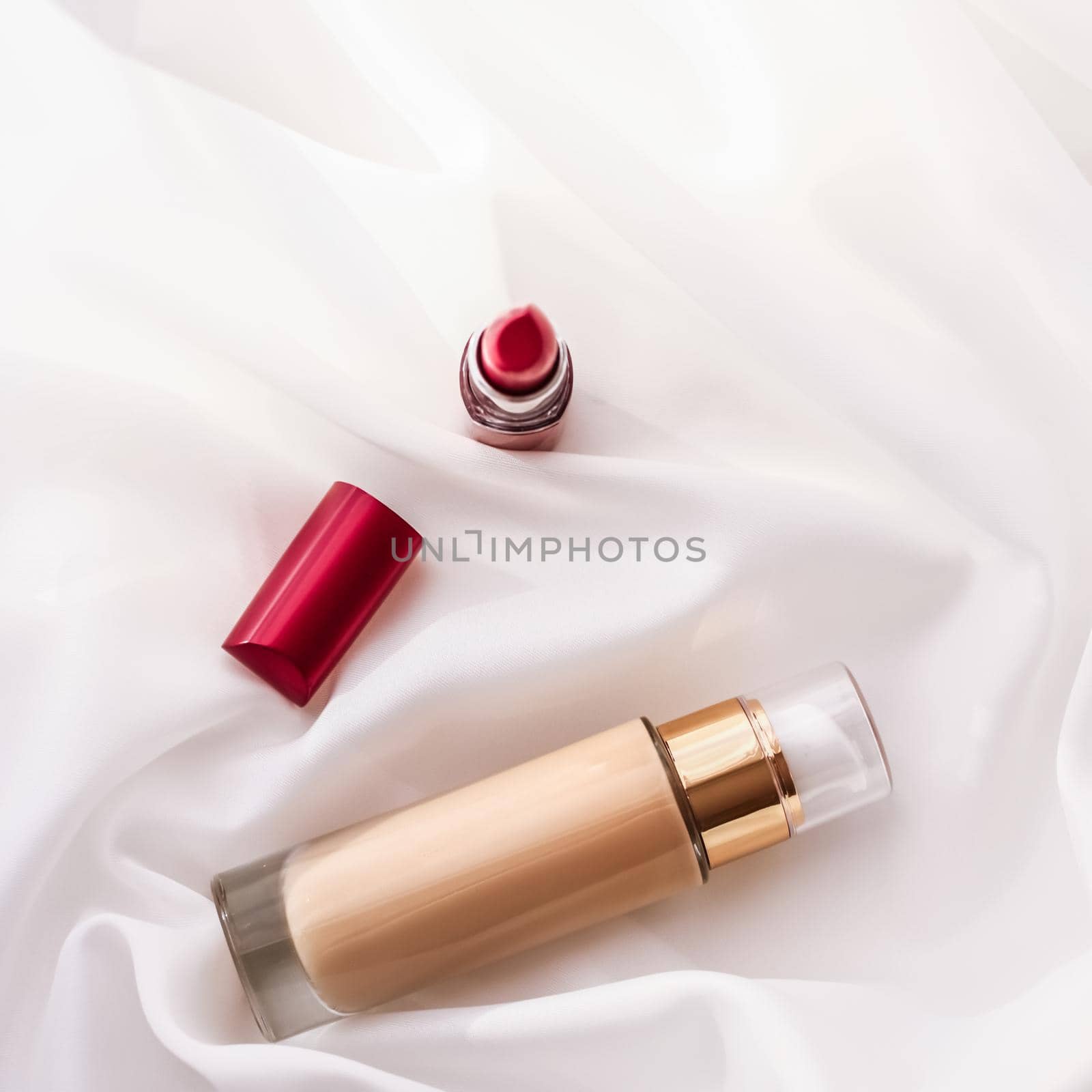 Beige tonal cream bottle make-up fluid foundation base and red lipstick on silk background, cosmetics products as luxury beauty brand holiday design by Anneleven