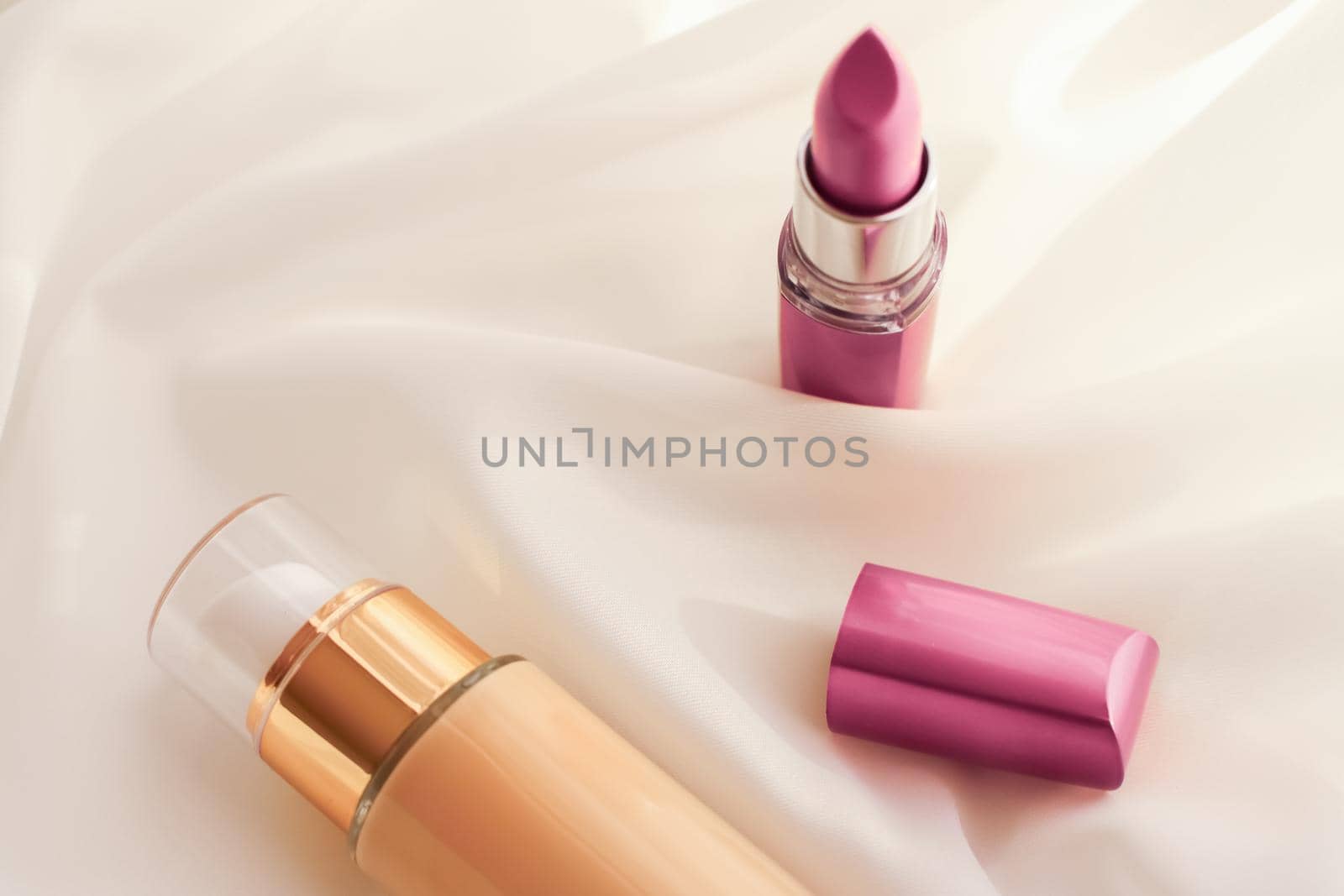 Beige tonal cream bottle make-up fluid foundation base and pink lipstick on silk background, cosmetics products as luxury beauty brand holiday design by Anneleven