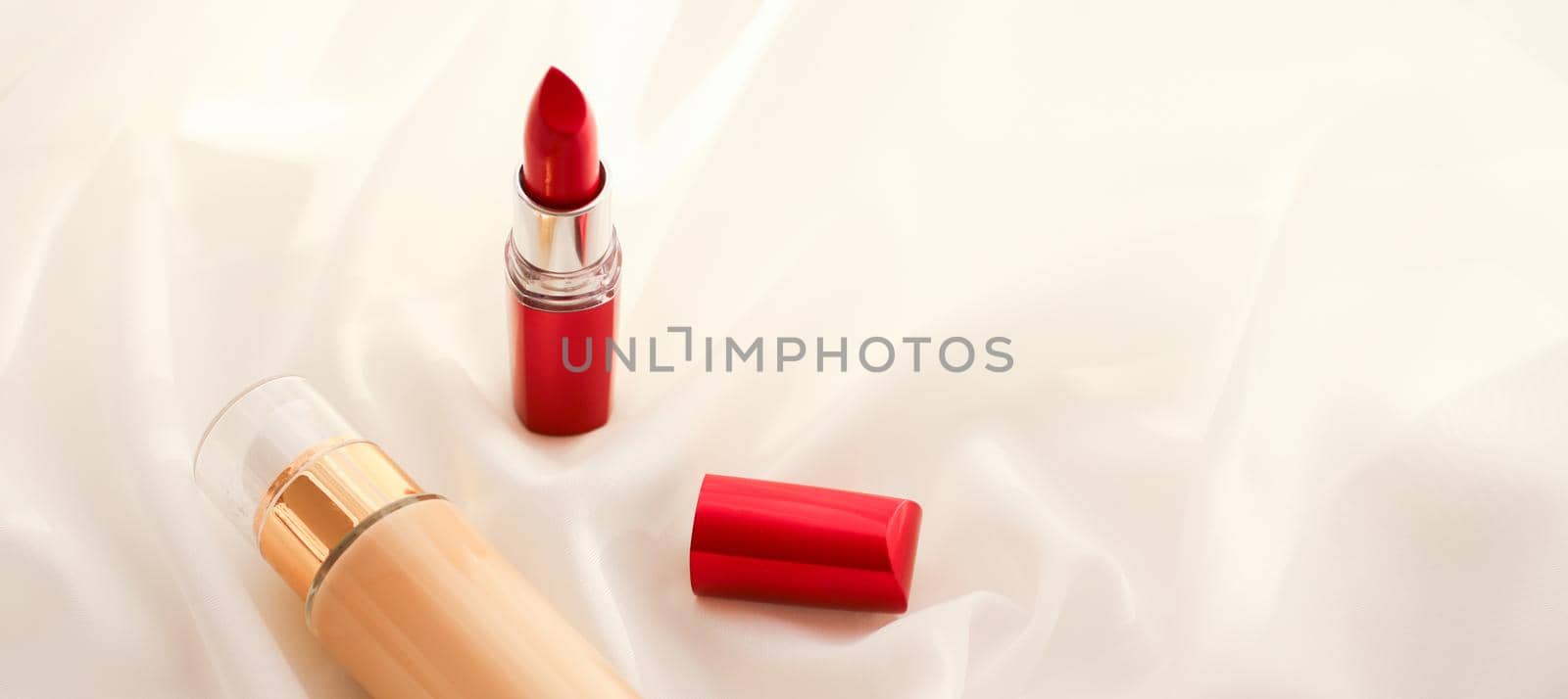 Beige tonal cream bottle make-up fluid foundation base and red lipstick on silk background, cosmetics products as luxury beauty brand holiday design by Anneleven