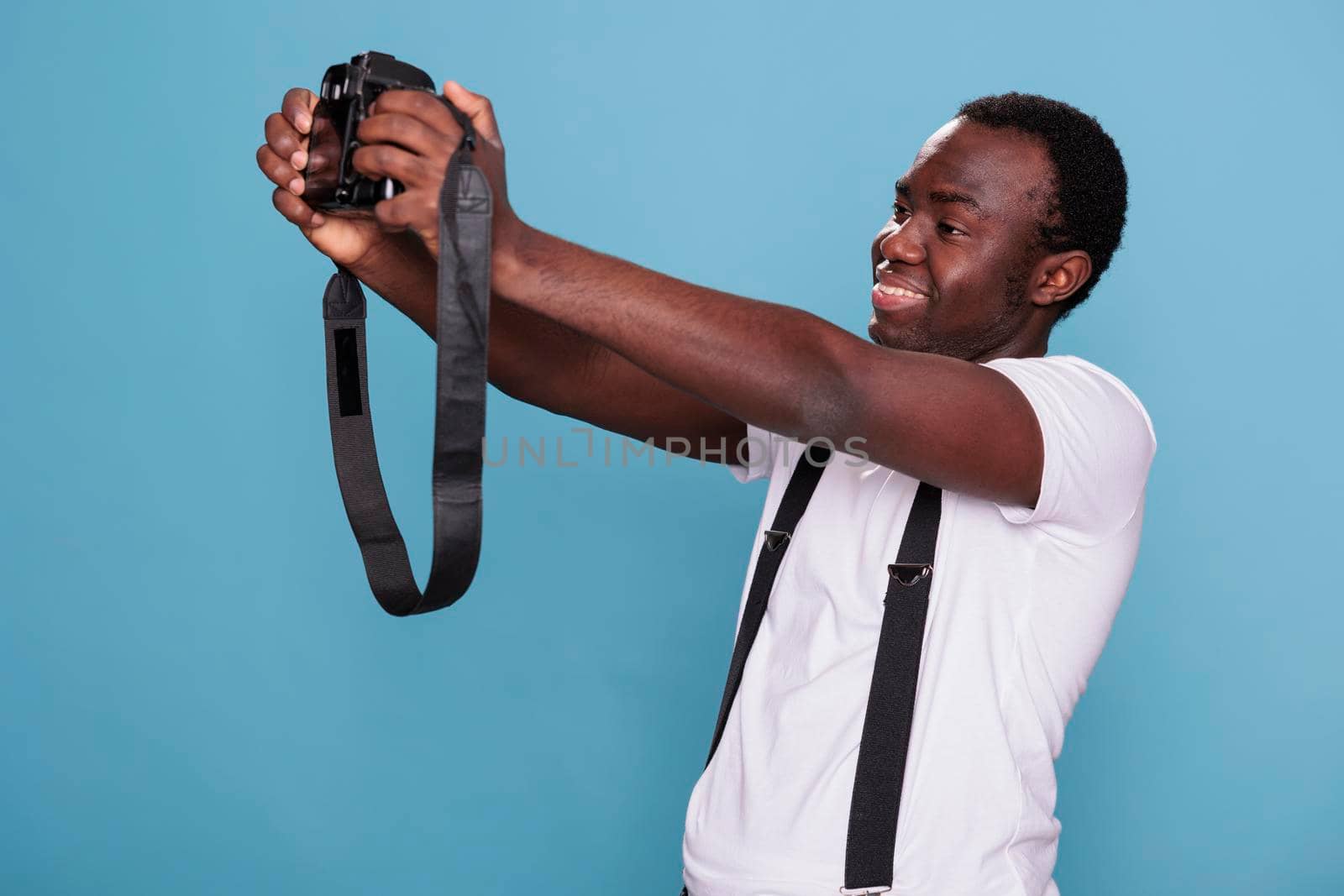 Joyful photography enthusiast taking selfie photo with DSLR camera by DCStudio