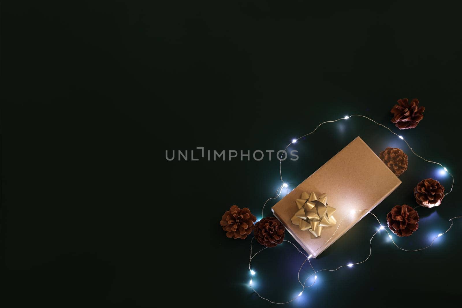Christmas composition. Xmas background. Christmas gift and decoration elements on the dark background, fairy lights. Free space for text, copy space. Flat lay, top view.