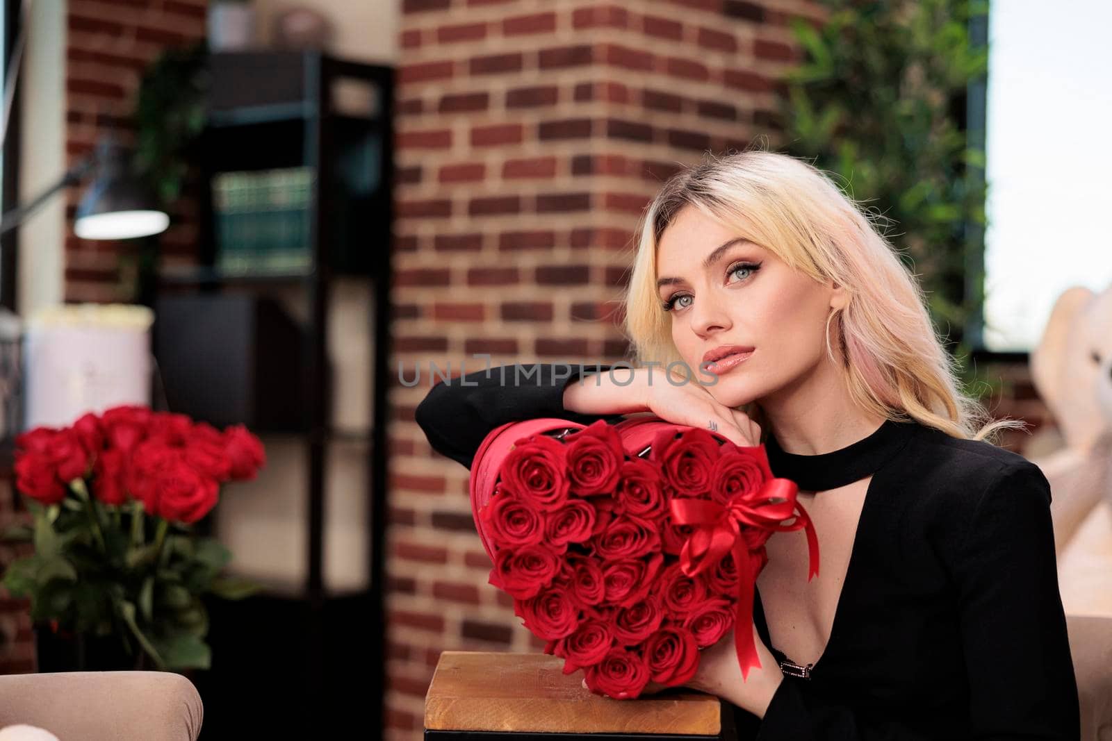 Beautiful thoughtful woman with roses romantic gift, valentines day date. Attractive blonde girlfriend with luxury presents posing, love holiday celebration, glowers delivery service