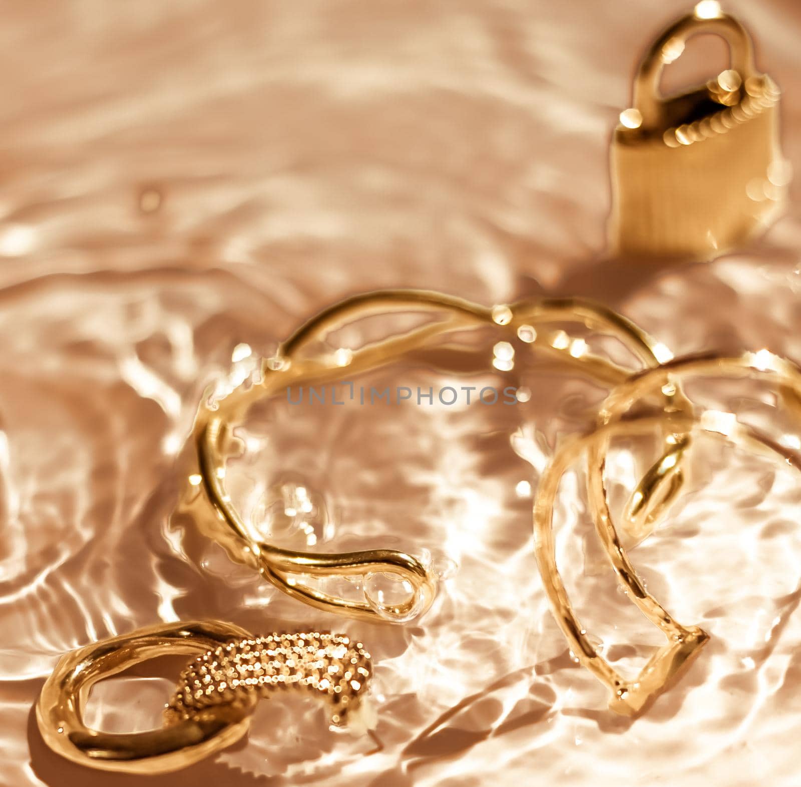 Golden bracelets, earrings, rings, jewelery on gold water background, luxury glamour and holiday beauty design for jewelry brand ads by Anneleven