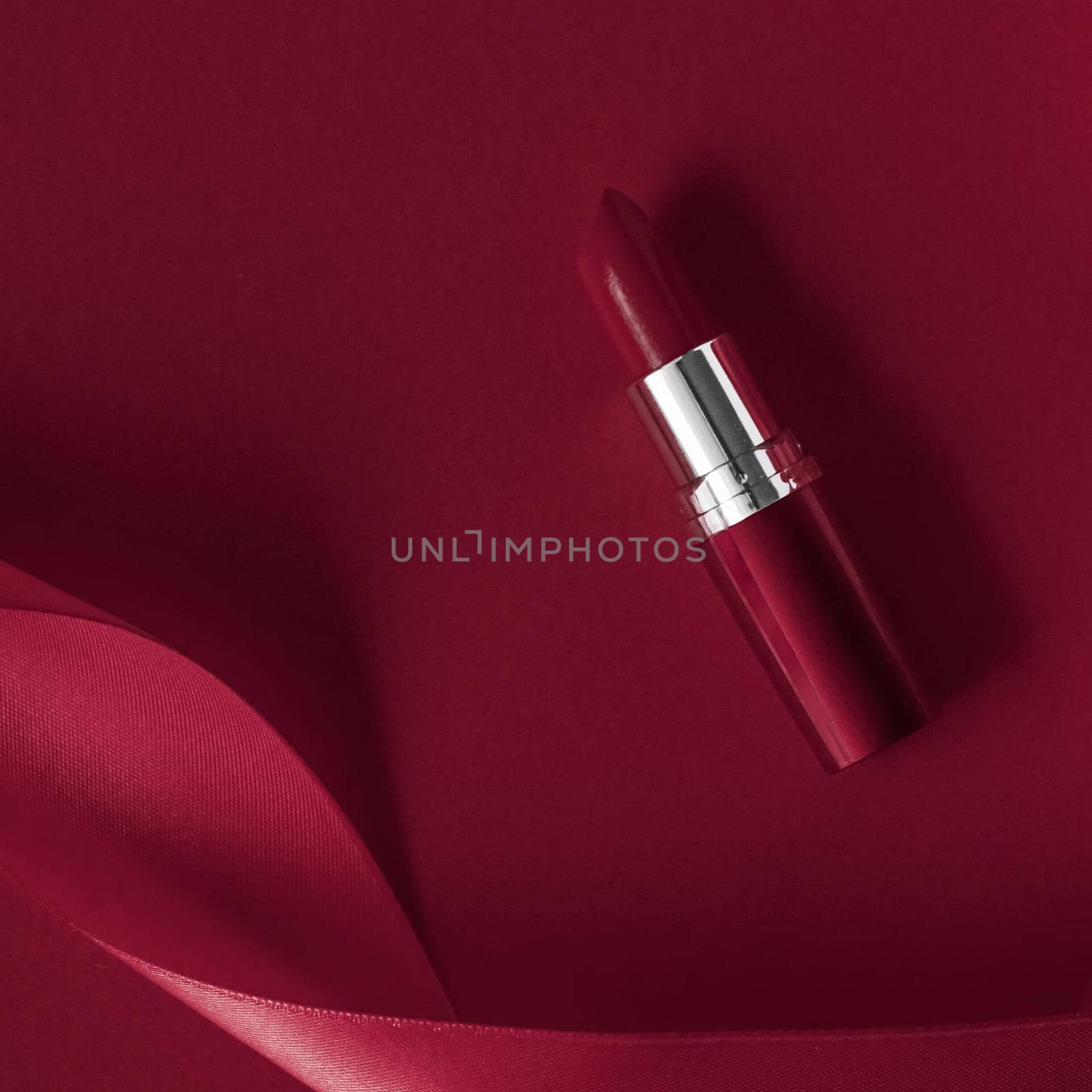 Cosmetic branding, glamour lip gloss and shopping sale concept - Luxury lipstick and silk ribbon on maroon holiday background, make-up and cosmetics flatlay for beauty brand product design
