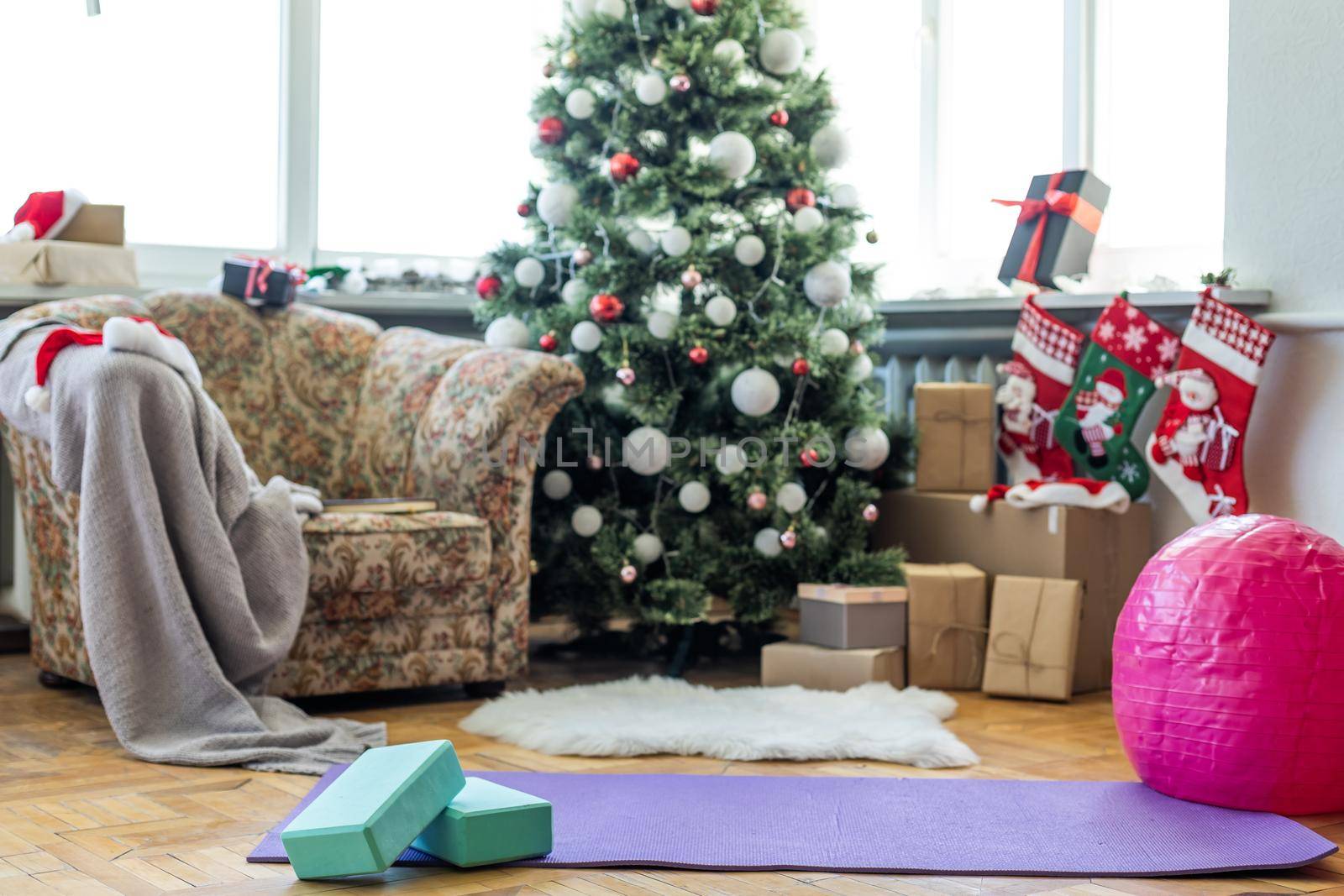 A blue yoga mat on a marble floor in a big living room. Christmas tree is on the background.