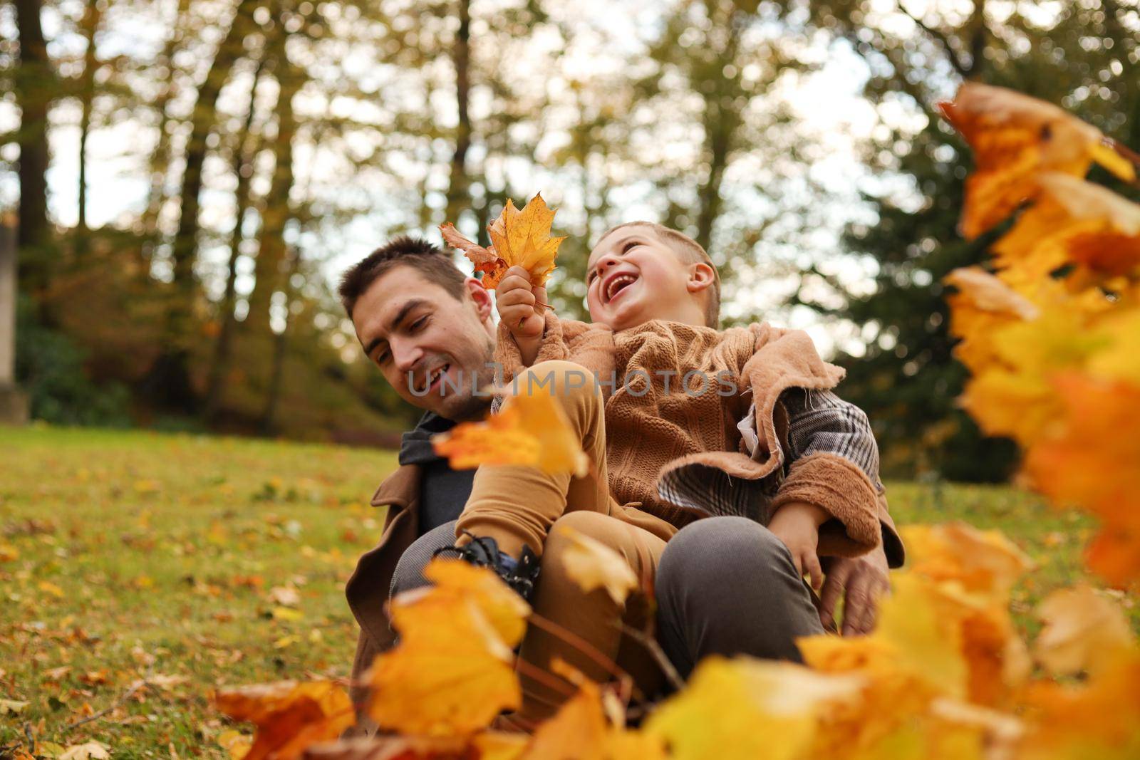 Outdoor fun in autumn. Father and son playing with autumn fallen leaves in park. by creativebird