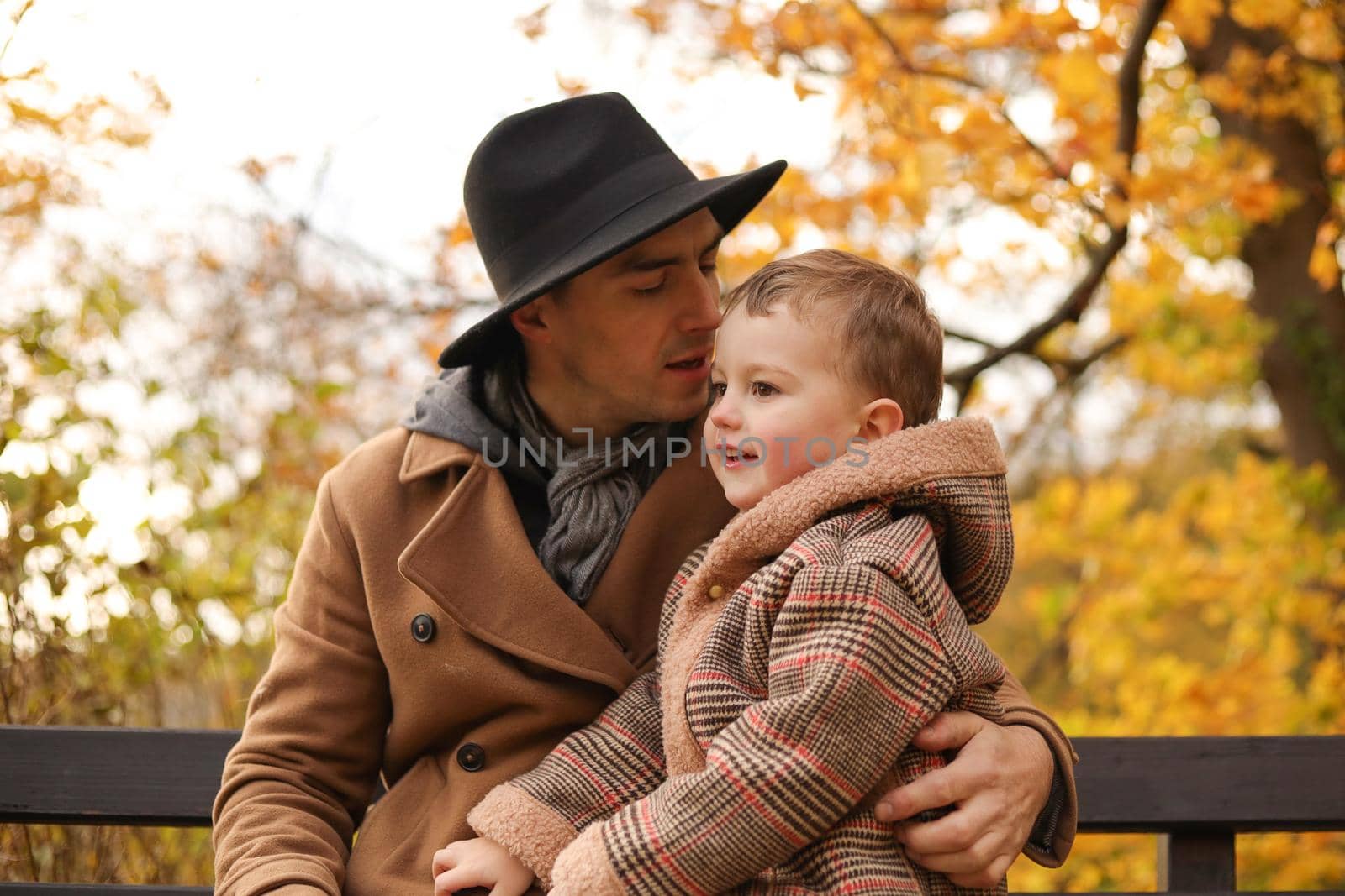 Father and son have fun together in park in autumn. Outdoor fun, autumn fallen leaves. Dad loves his boy