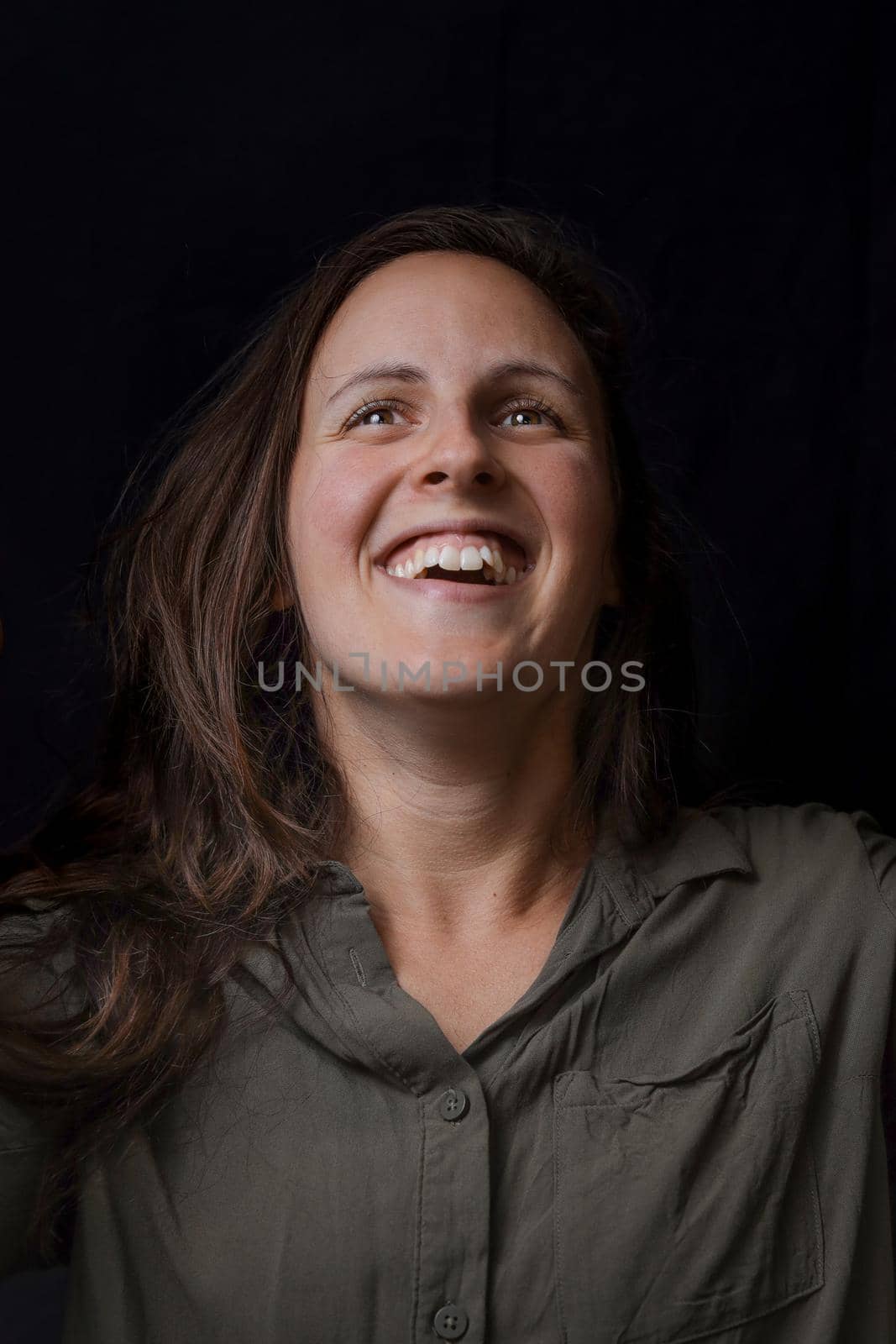 Cheerful happy young beautiful girl smiling laughing over black background. Close-up portrait of pretty young woman