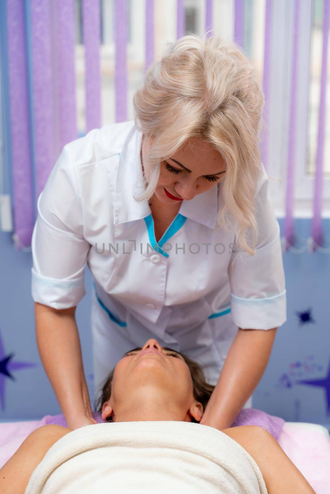 Masseur woman massages her shoulders. Woman getting a massage at the spa by Matiunina