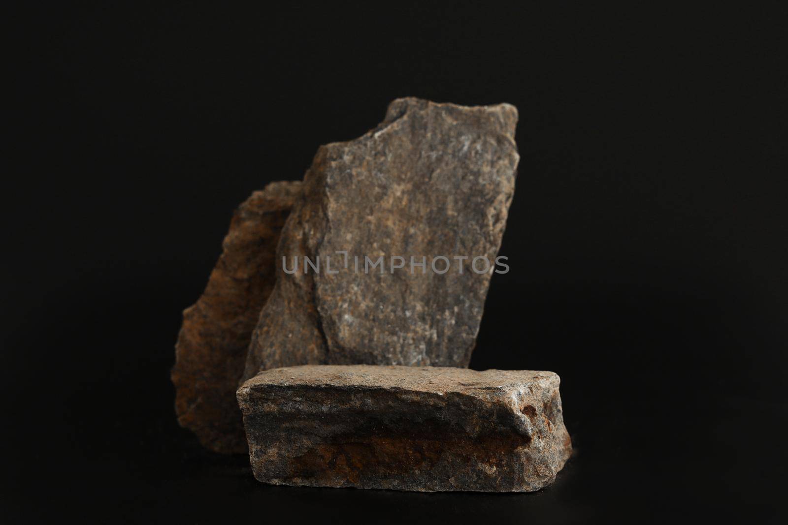 Rock podium on the black background. Stone podest for product, cosmetic presentation. Creative mock up. Pedestal or platform for beauty products