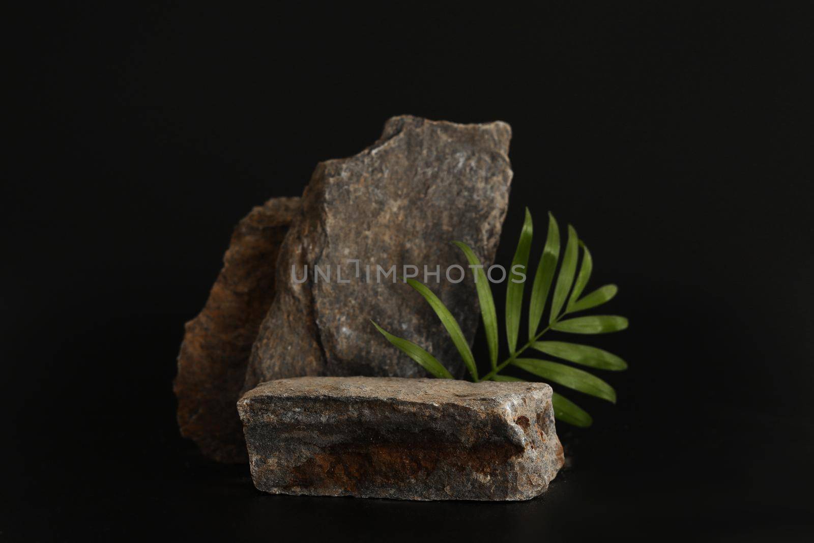 Rock podium on the black background with tropical leaves. Stone podest for product, cosmetic presentation. Creative mock up. Pedestal or platform for beauty products. by creativebird