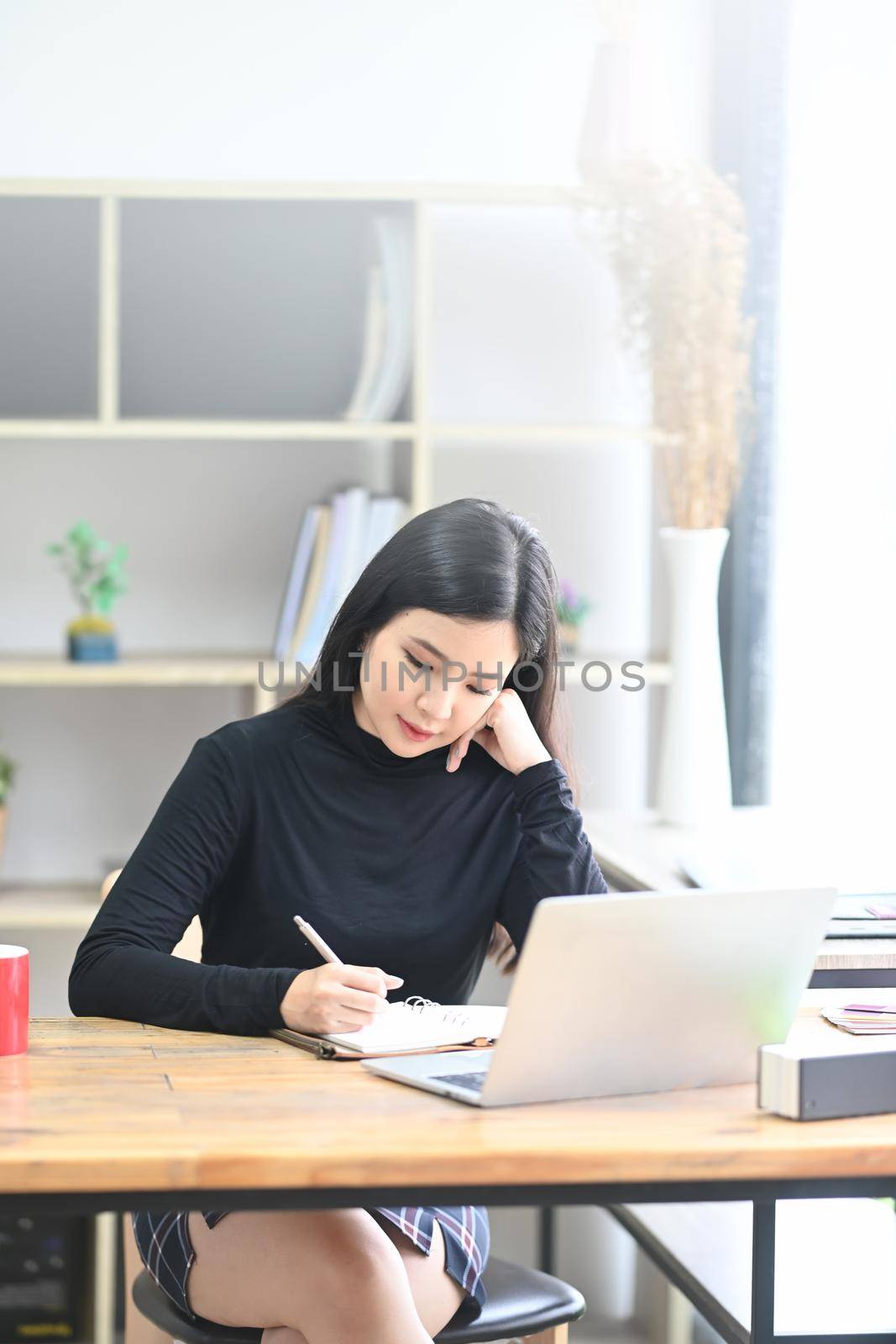 Portrait of beautiful woman designer sitting in creative office and working with laptop computer.