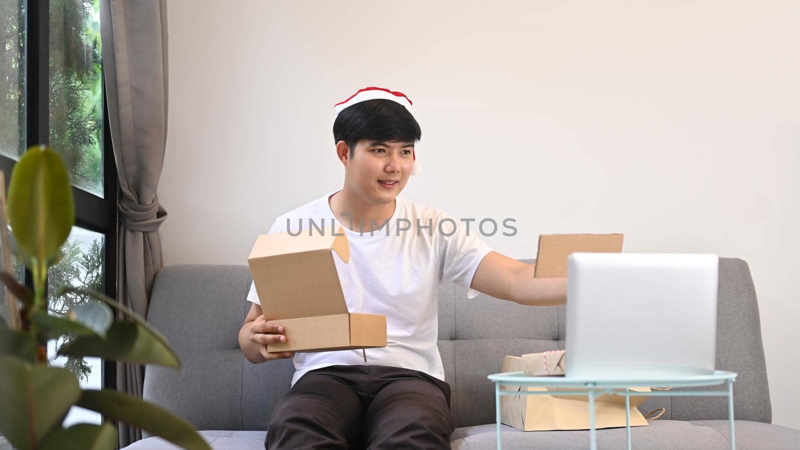 Happy young man showing Christmas present during video call with his family.