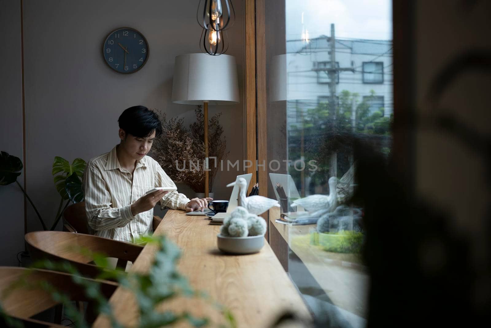 Young asian man sitting in cafe and using smart phone.