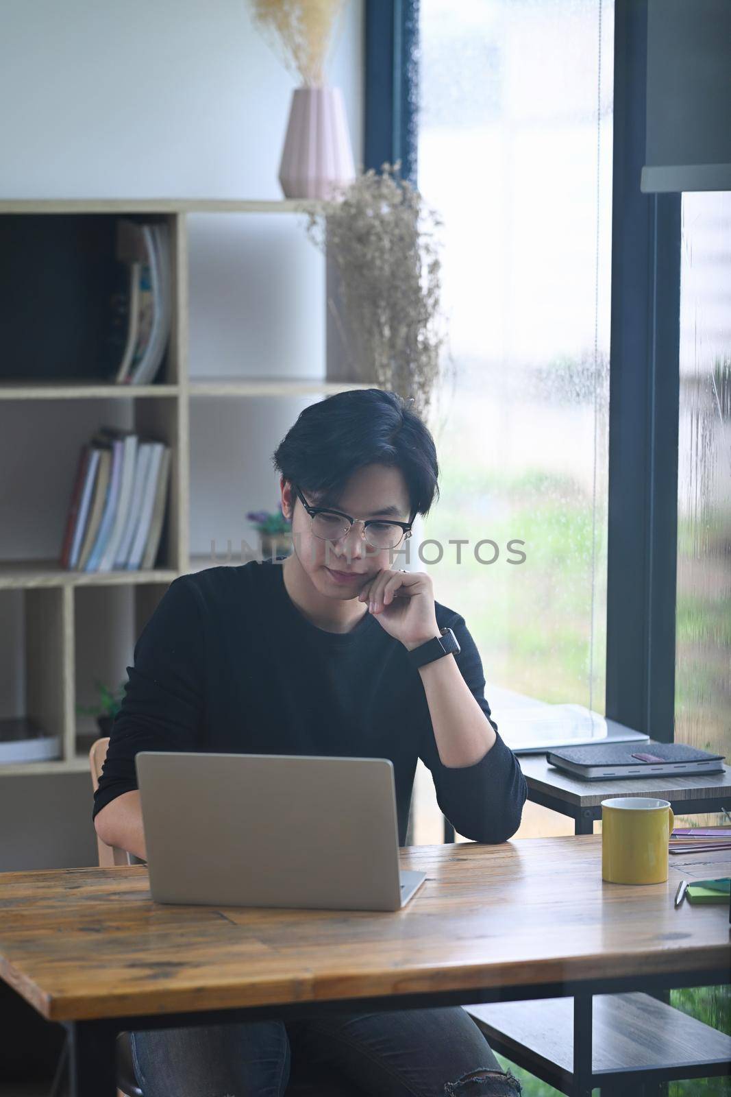 Handsome man designer sitting in creative office and working with laptop computer. by prathanchorruangsak