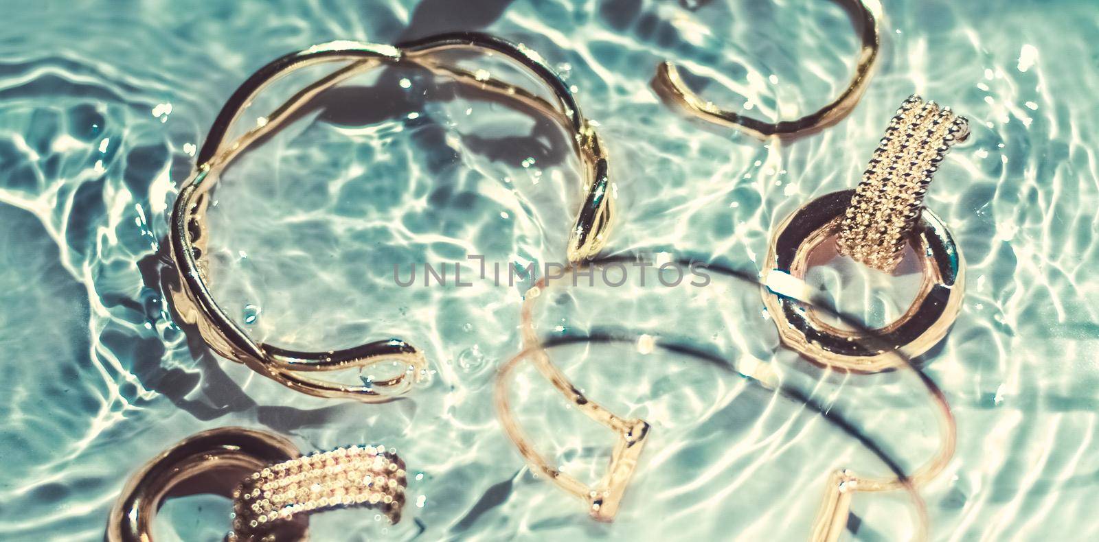 Golden bracelets, earrings, rings, jewelery on emerald water background, luxury glamour and holiday beauty design for jewelry brand ads by Anneleven