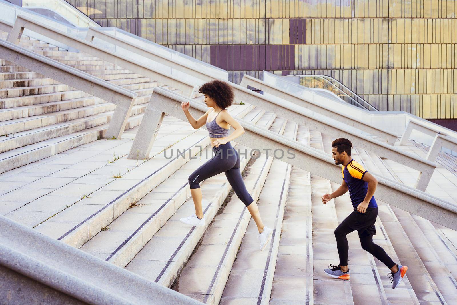 young latin sports woman and afro american man running up stairs in the city. fitness, urban sports workout and healthy lifestyle concept, copy space for text