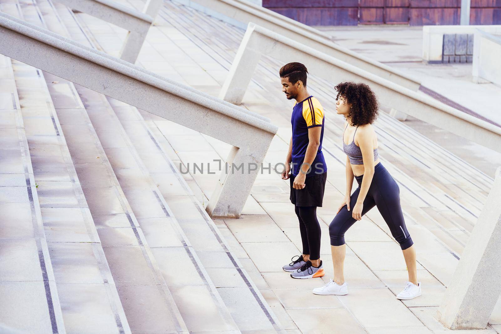 interracial couple of runners preparing to train on the city stairs. fitness, urban sports workout and healthy lifestyle concept, copy space for tex