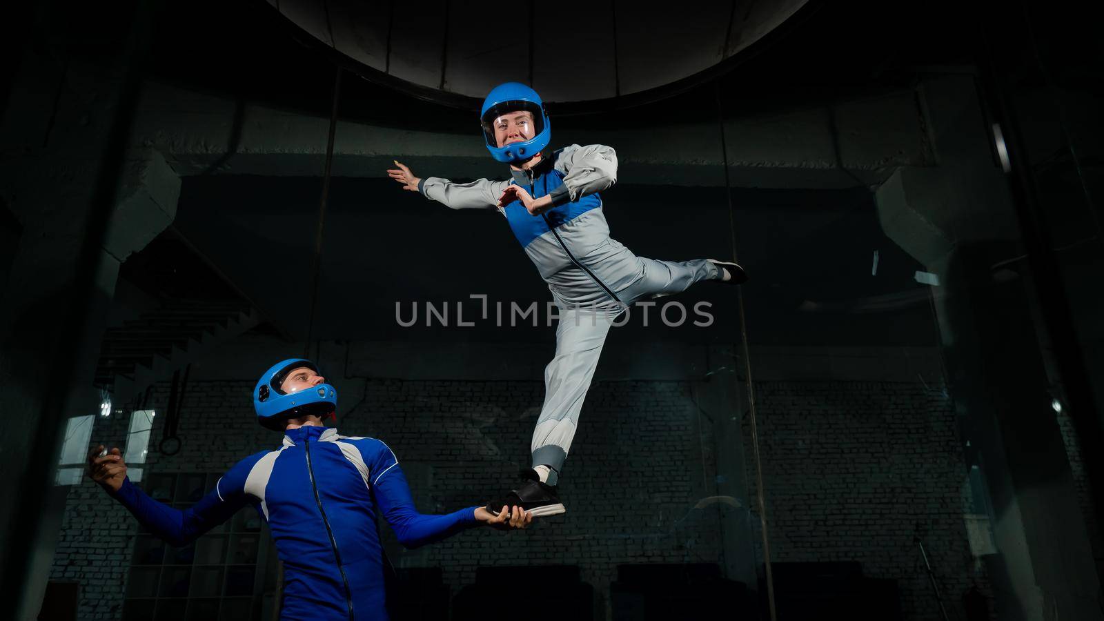 A man teaches a woman how to fly in a wind tunnel. Free fall simulator