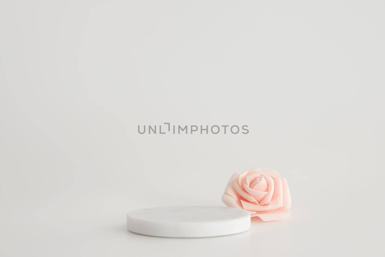 White marble podium on the white background with pink flowers. Podium for product, cosmetic presentation. Creative mock up. Pedestal or platform for beauty products. by creativebird