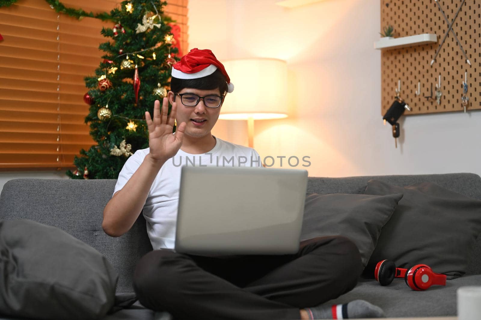 Smiling man wearing Santa hat having video calling with family via laptop computer.