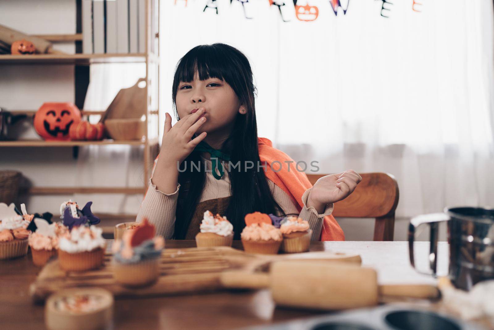 Young girl at Halloween making treats and cupcake on table. Happy Halloween day by itchaznong