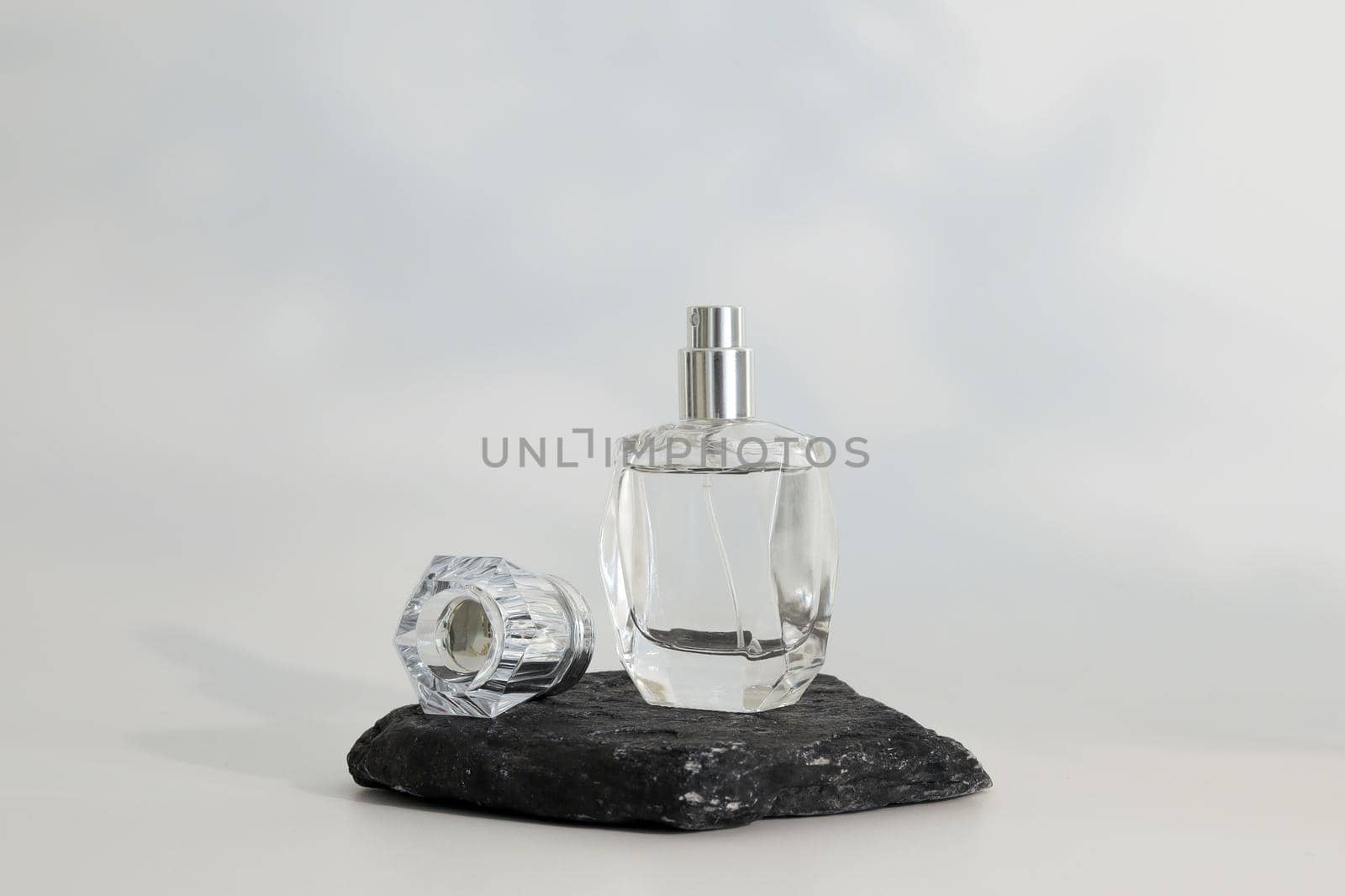 Unbranded perfume bottle standing on stone podium. Perfume presentation on the white background. Mockup. Trending concept in natural materials. Women's and men's essence. Natural cosmetic. by creativebird