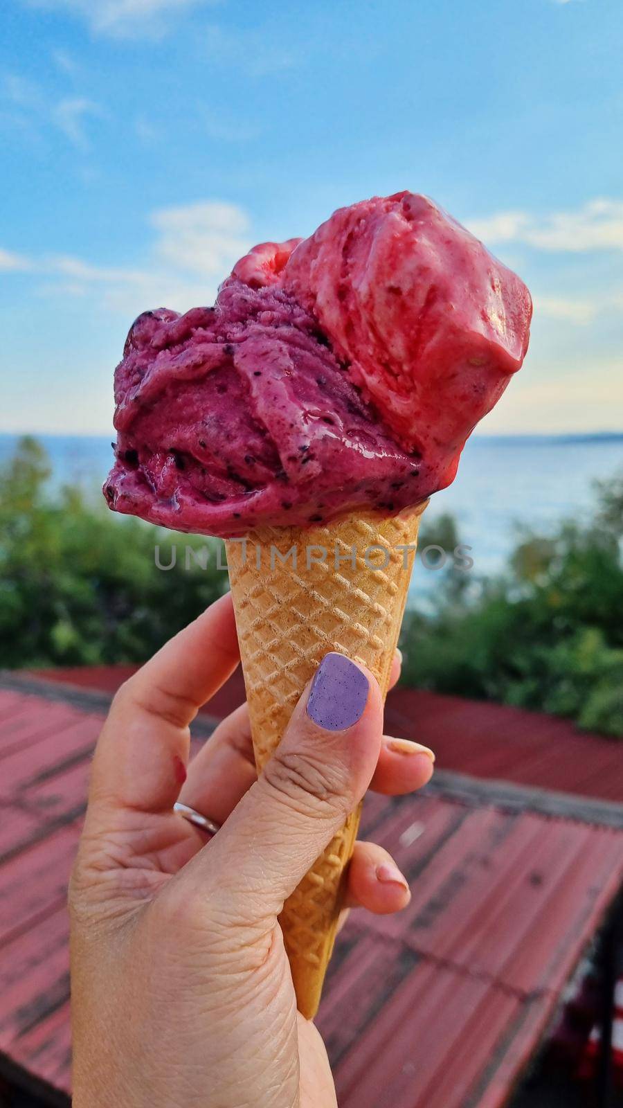Gelato ice cream cone held up to the hot summer city by anytka